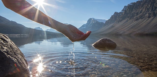 Woman touching water in natural lake